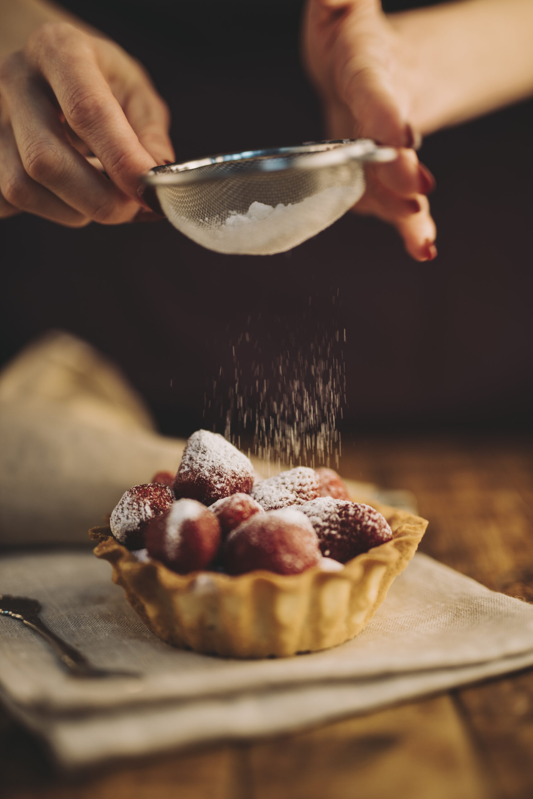 close-up-woman-dusting-sugar-powder-strawberry-tart