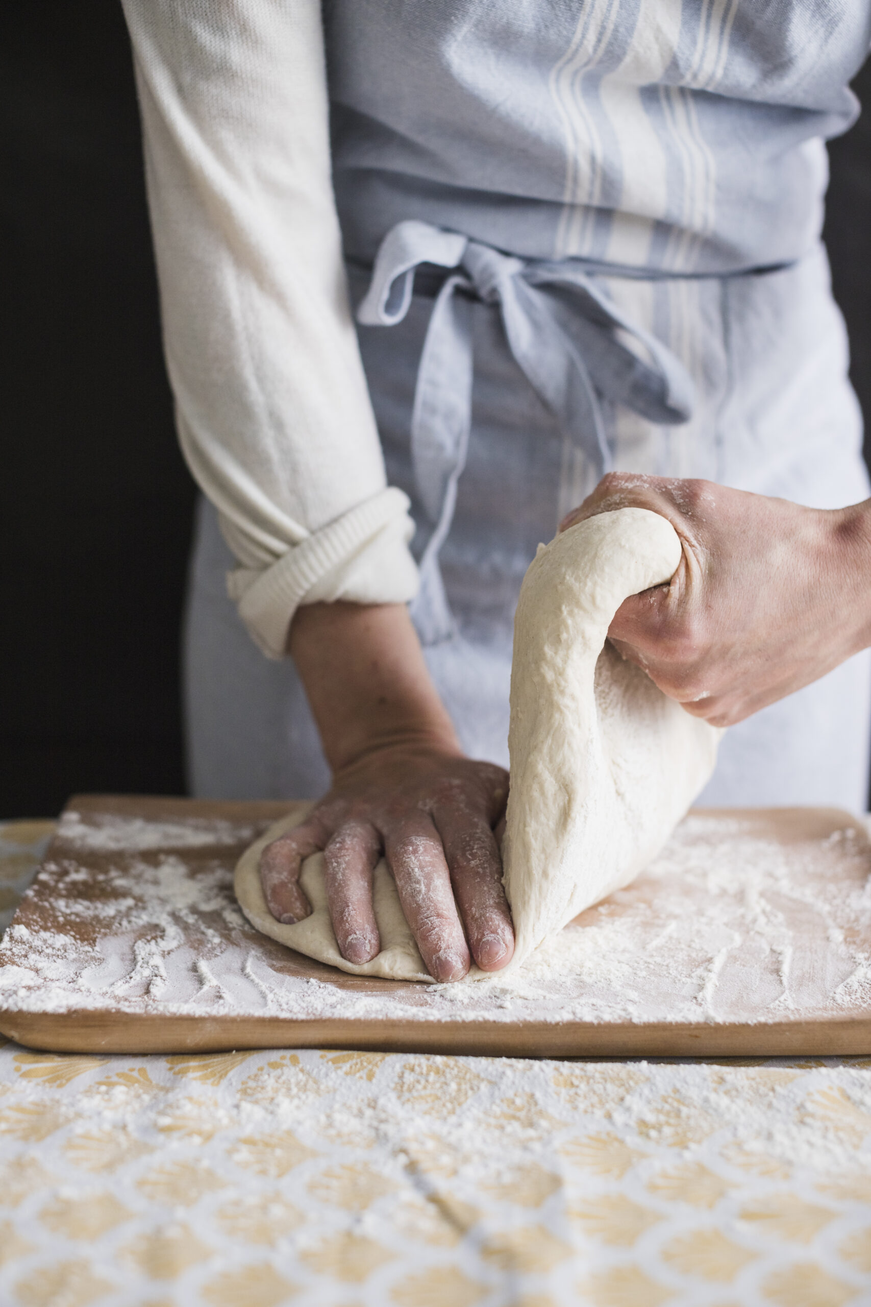 female-baker-kneading-dough-with-flour-chopping-board
