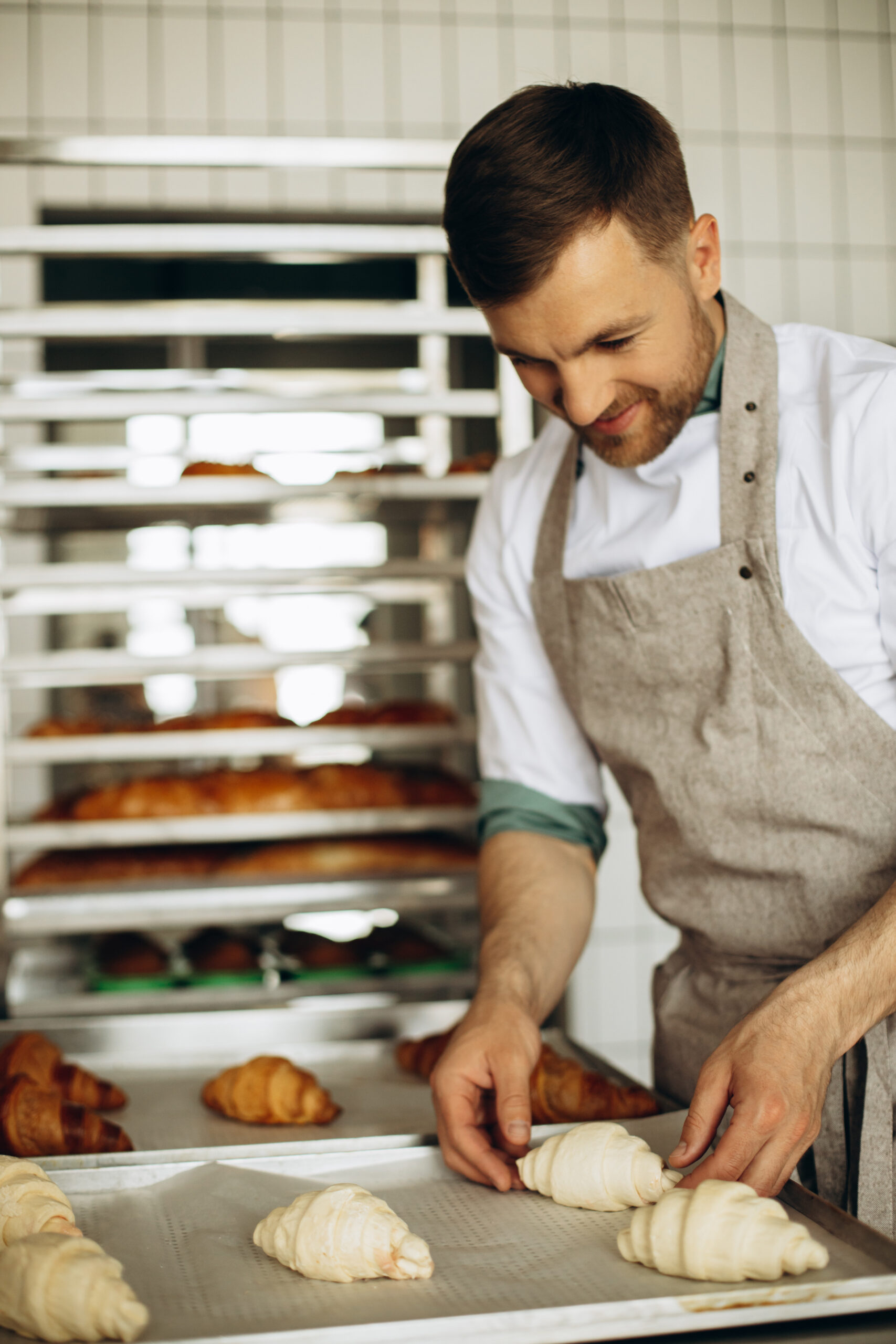 Handsome baker preparing croissants at the bake house